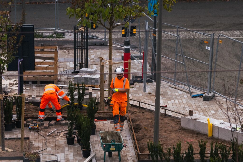 Två stenläggare från Astrimant ler medan de lägger marksten vid resecentrum Karlstad